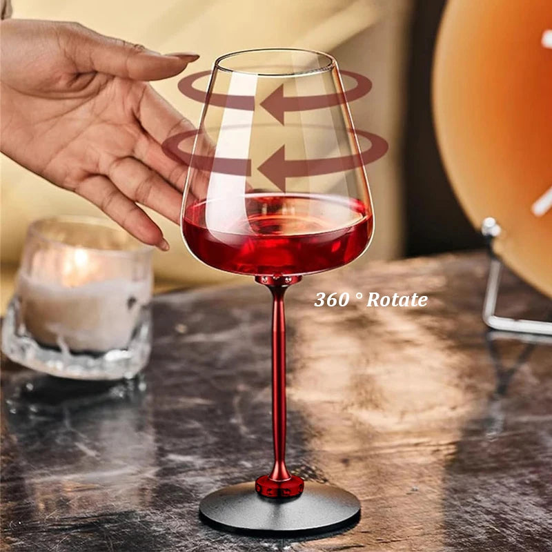Red wine glass with a hand holding it, on a wooden surface with a candle in the background.