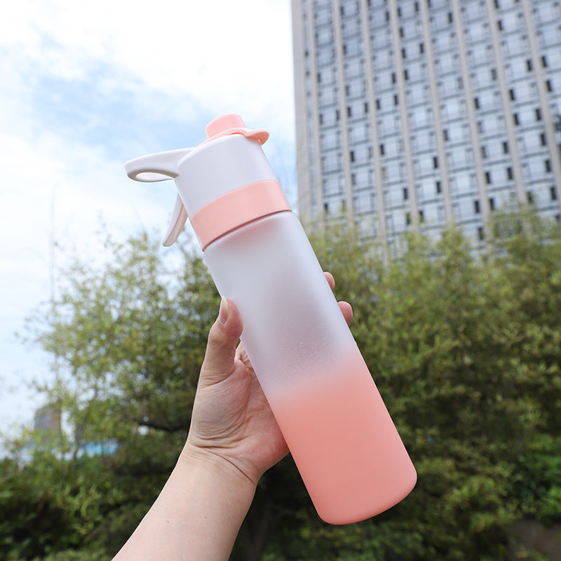 Gradient pink and white spray bottle held in a hand with a cityscape background