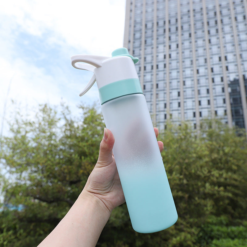 Gradient blue and white water bottle held in front of a building and trees