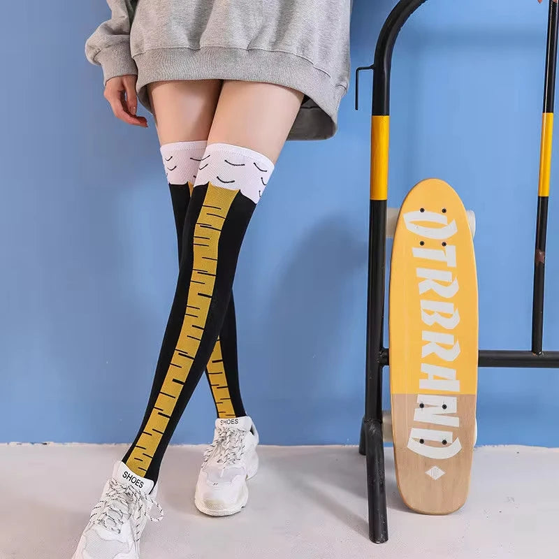 Person wearing black knee-high socks with yellow ruler design, standing next to a skateboard with 'OTRBREED' branding.