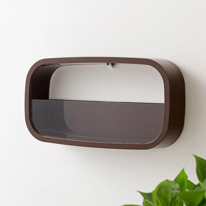 Rectangular wall mirror with brown frame on a white wall, partially obscured by green leaves.