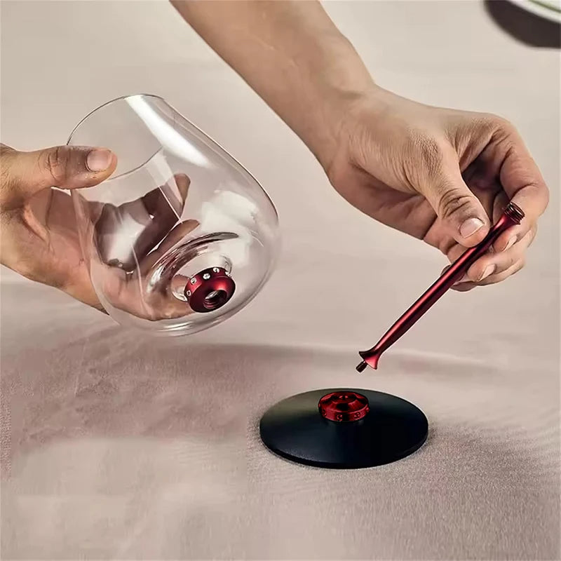Person using a red wine aerator to degass a glass of wine on a neutral background
