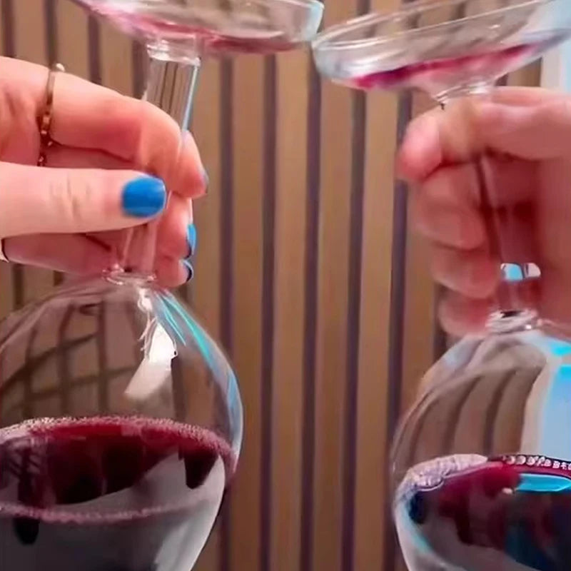 Two hands holding wine glasses with red wine against a striped background