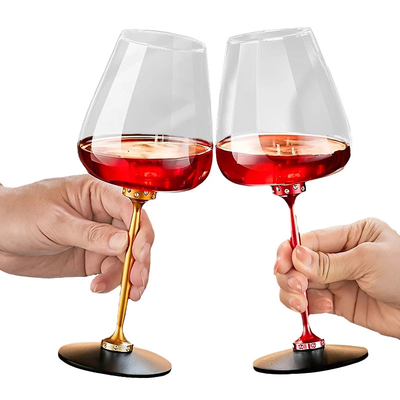 Two hands holding red wine glasses with gold and red stems on a white background