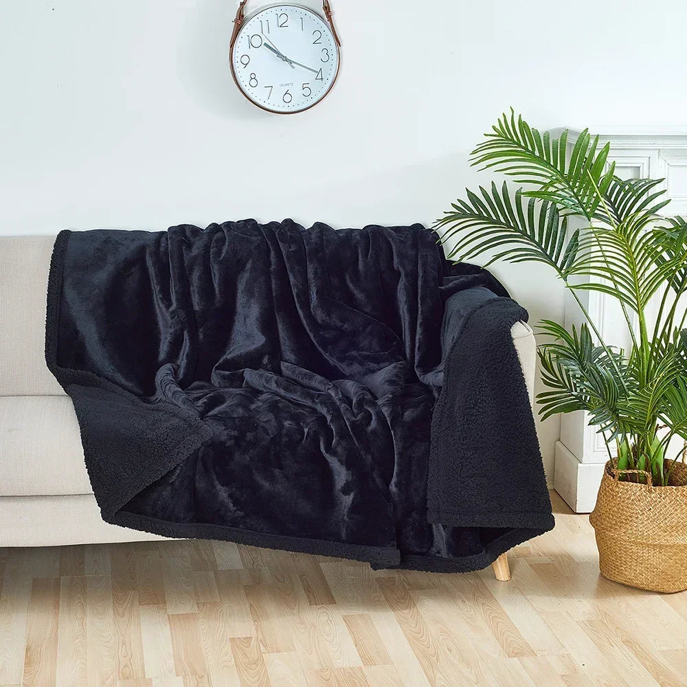 Black blanket draped over a chair in a living room with a clock and plant in the background.