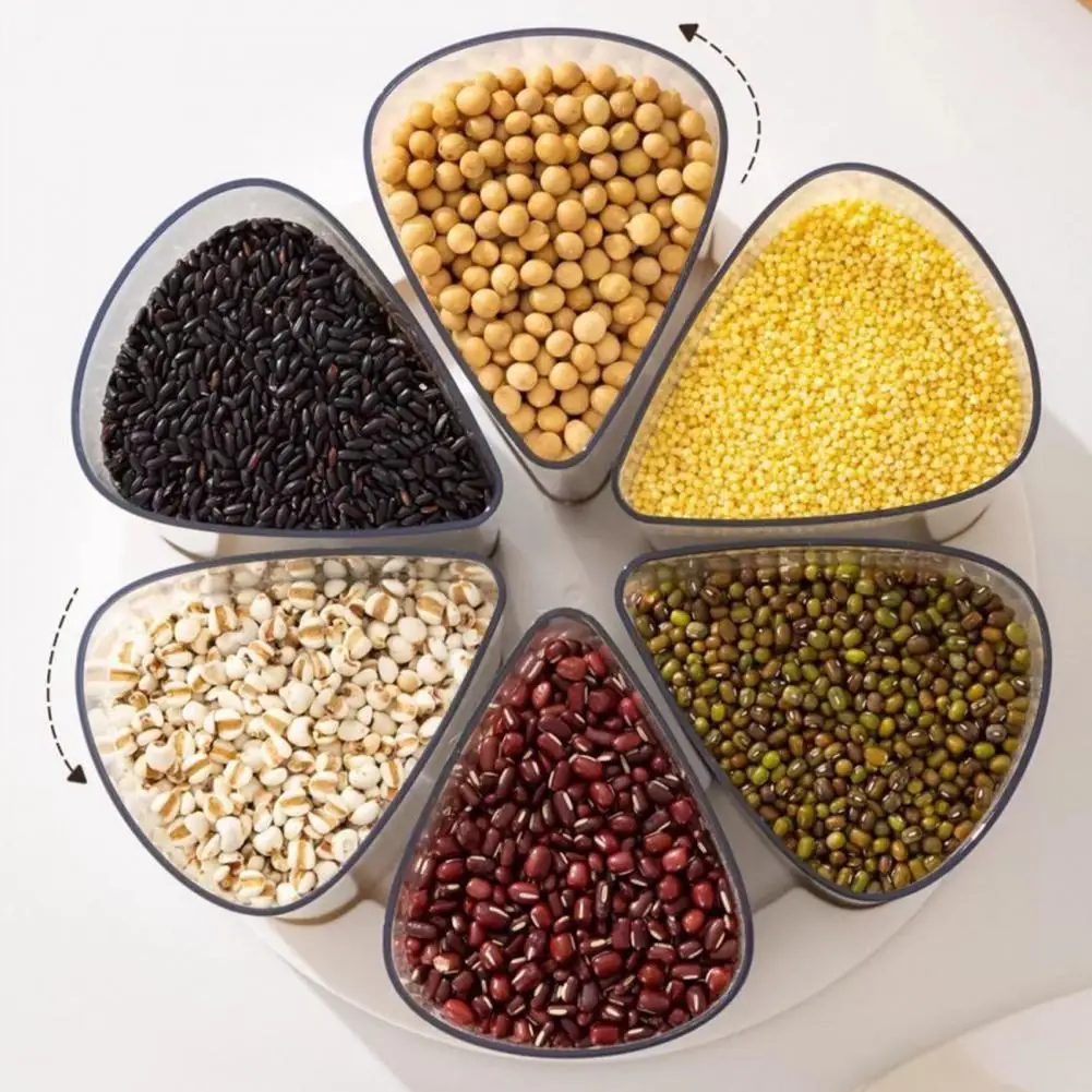 Six triangular clear plastic containers arranged in a circle on a white surface, filled with different grains and legumes: black rice, soybeans, millet, barley, red beans, and green mung beans. Arrows indicate rotation.