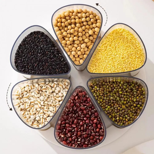 Six triangular clear plastic containers arranged in a circle on a white surface, filled with different grains and legumes: black rice, soybeans, millet, barley, red beans, and green mung beans. Arrows indicate rotation.
