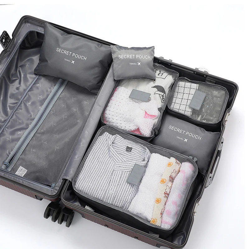 Open suitcase with travel packing cubes labeled 'Secret Pouch' on a white background