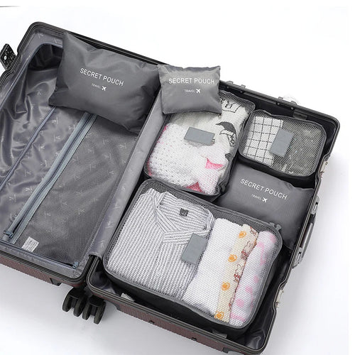 Open suitcase with travel packing cubes labeled 'Secret Pouch' on a white background
