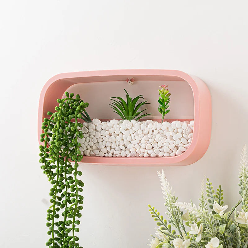 Pink wall shelf with plants and pebbles on a light background