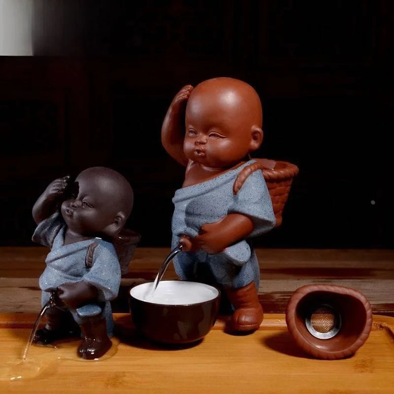 Two ceramic figures of children with a bowl on a wooden surface.