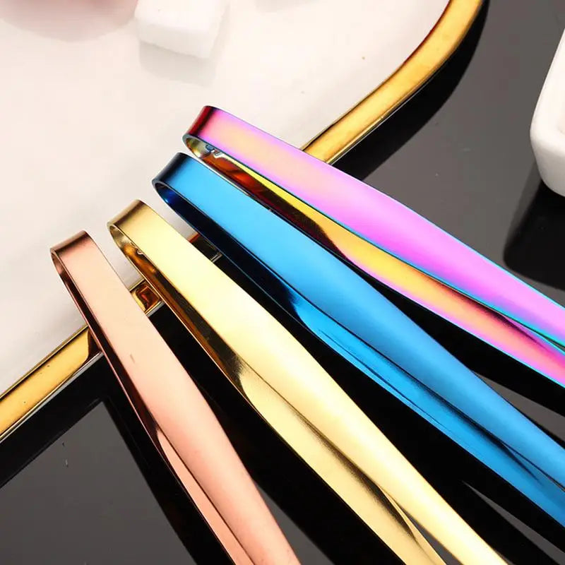 Metallic hair clips in gold, rose gold, and rainbow colors on a reflective surface.