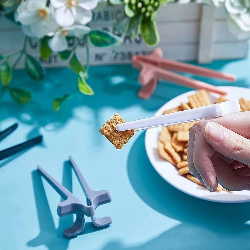 Hand holding a cracker with a white stick over a bowl of crackers on a blue surface with flowers in the background.
