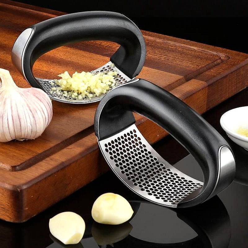 Stainless steel garlic press crushing fresh garlic cloves