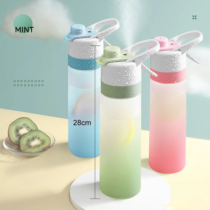 Three gradient-colored water bottles with sprayer lids on a light blue background, with kiwi slices and a plate in the foreground.