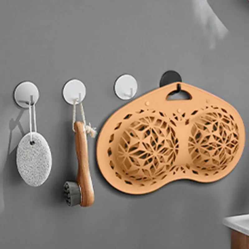 Wall-mounted bath tools including a loofah, scrubber, and mesh scrubber on a gray wall.