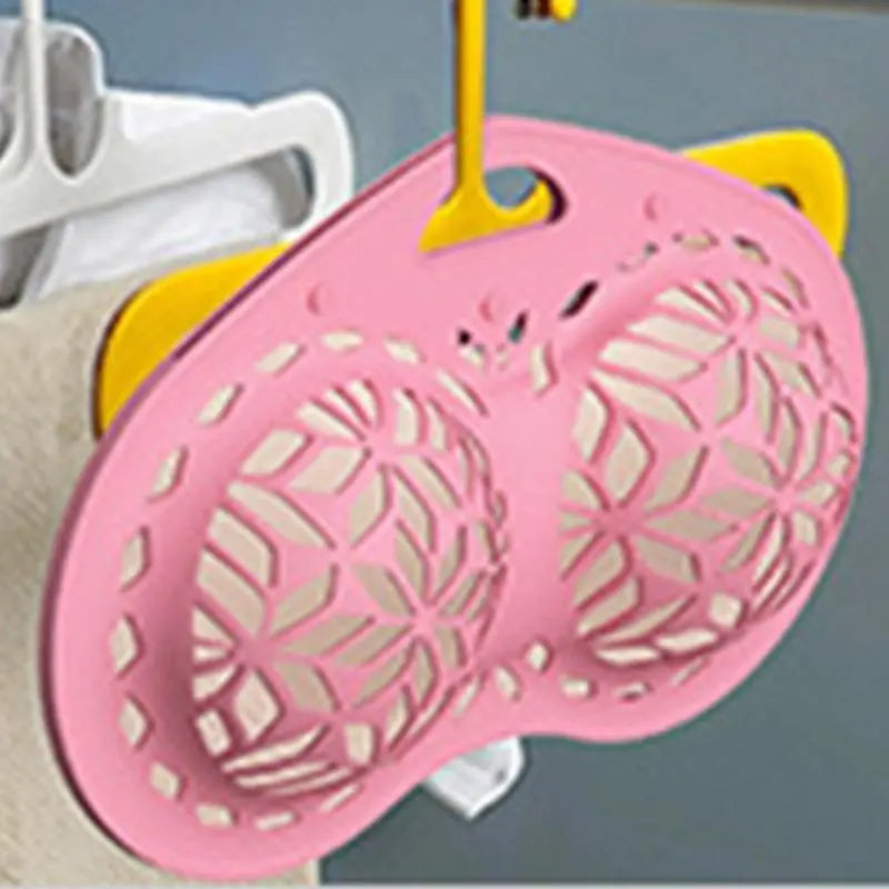 Pink silicone mat with geometric pattern on a hook against a gray background