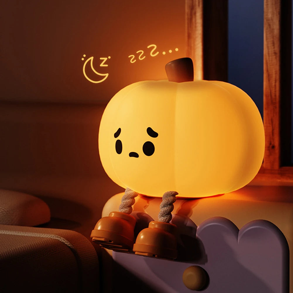 Cute pumpkin-shaped night light with a face on a soft surface, emitting a warm glow.