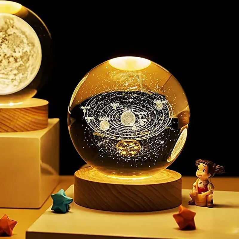 Glowing crystal ball with solar system design on a wooden base, surrounded by decorative items.