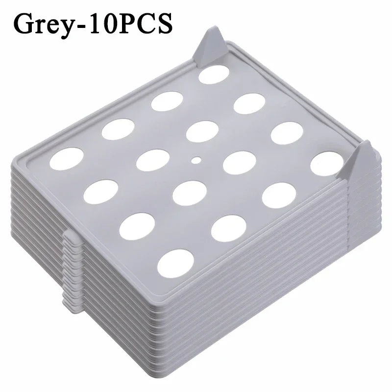 Stack of gray plastic trays with multiple holes on a white background