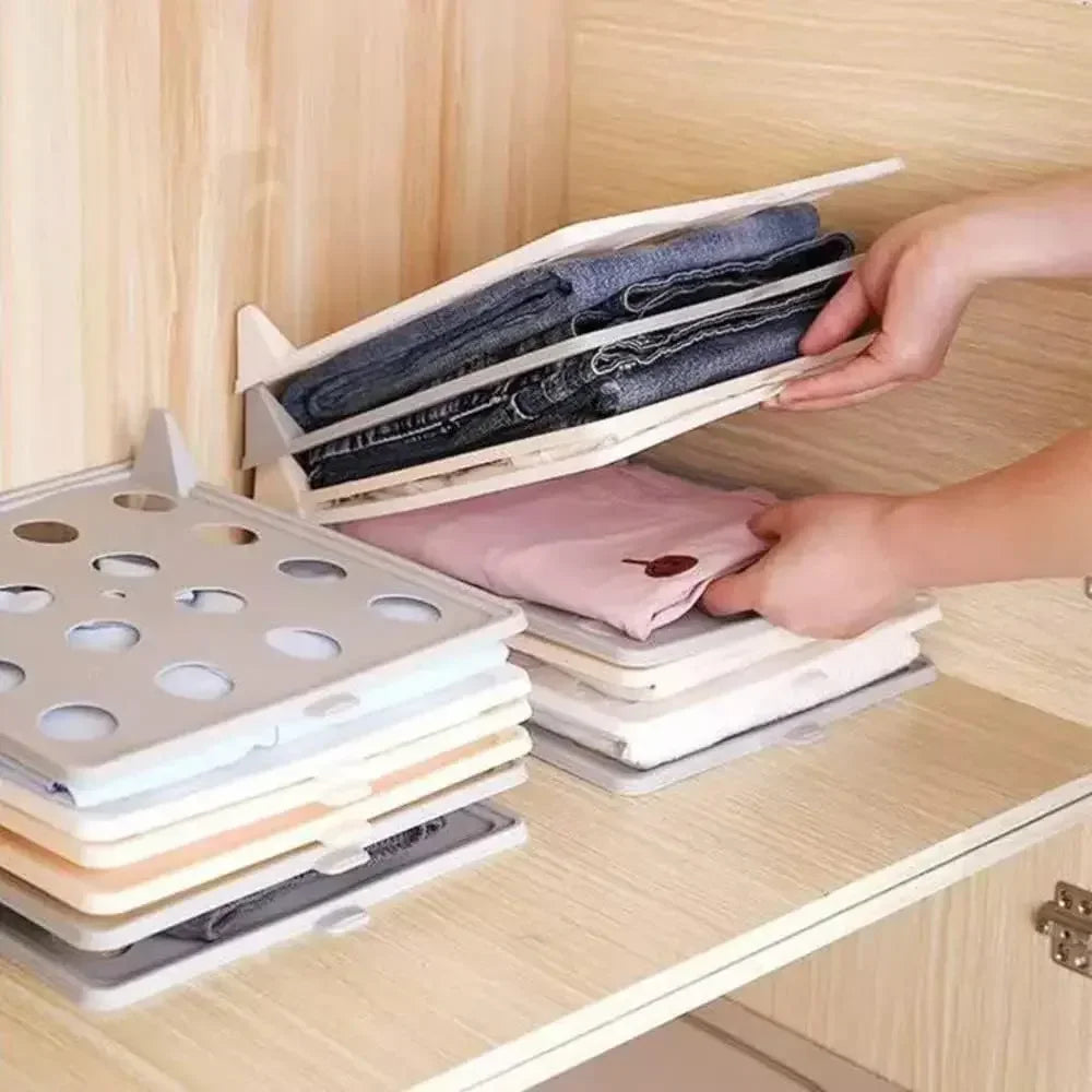 Foldable clothing organizer being used to sort folded clothes on a wooden surface.