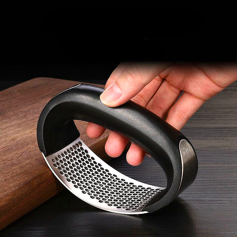 Hand holding a black and silver kitchen grater on a wooden surface